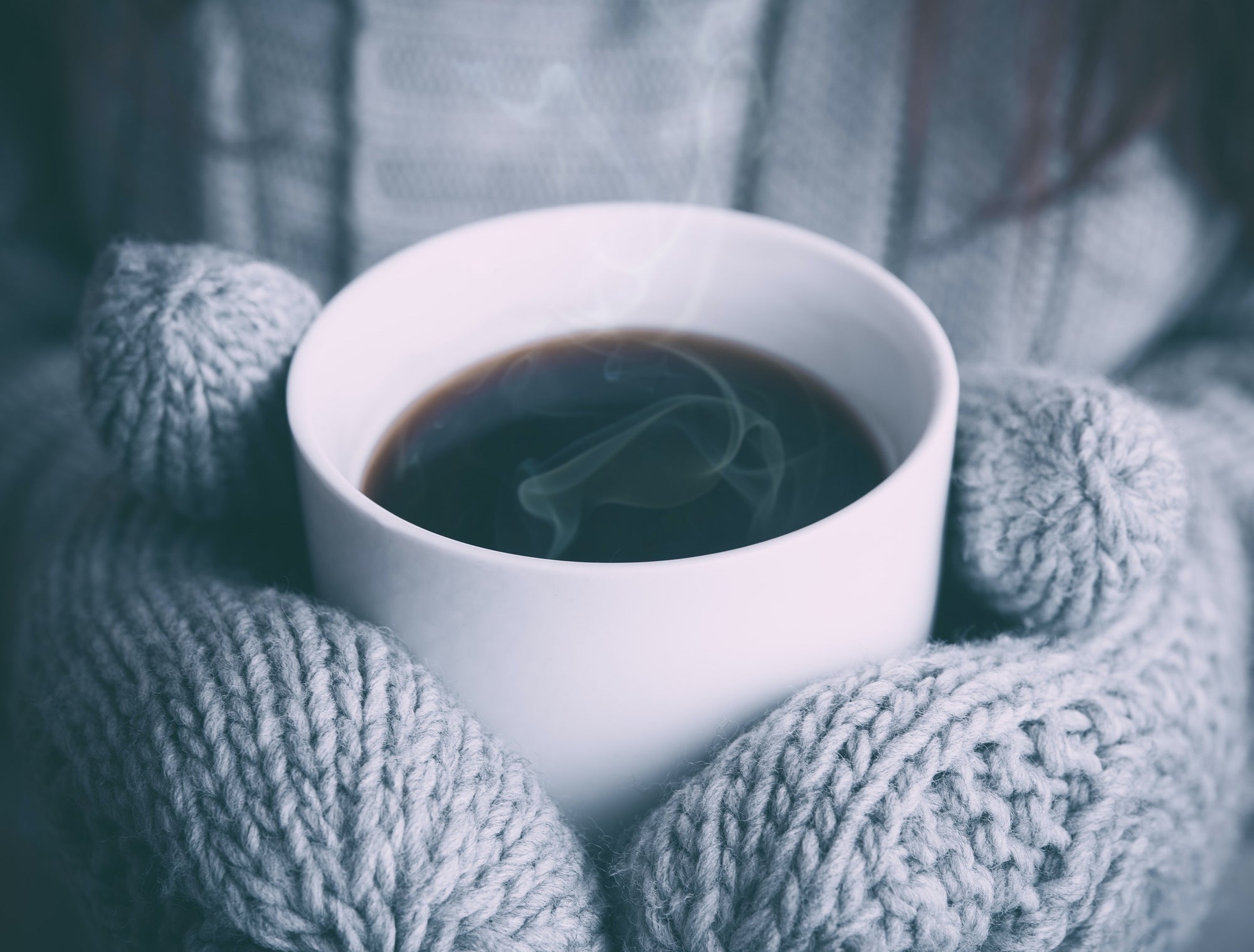 Kaffeetasse von dicken Winterhandschuhen gehalten